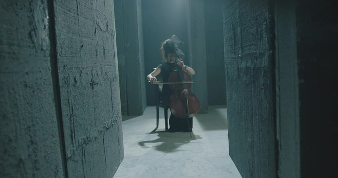 4K Black dressed young girl playing the violoncello in mystic place . Alone female musician plays the violin . Mystical scene . Shot on ARRI ALEXA Cinema Camera in slow motion .