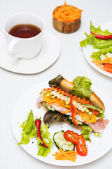 Banh mi sandwiches with various stuffing and cup of tea. Traditional vietnamese breakfast. Trendy still life in light colors.
