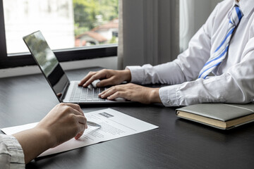 The atmosphere of the job interview room has HR and job applicants checking resumes, HR is typing applicants' information into laptops to send information to the system to the department manager.