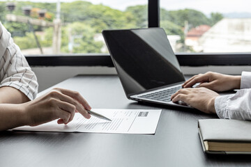 The atmosphere of the job interview room has HR and job applicants checking resumes, HR is typing applicants' information into laptops to send information to the system to the department manager.