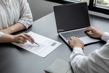 The atmosphere of the job interview room has HR and job applicants checking resumes, HR is typing...