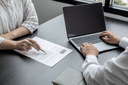 The atmosphere of the job interview room has HR and job applicants checking resumes, HR is typing applicants' information into laptops to send information to the system to the department manager.
