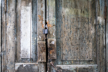 Fragment of an old green wooden door with a handle and a lock with peeling paint