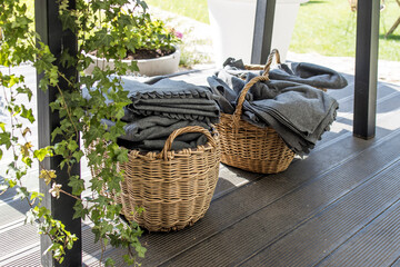 Wicker baskets with gray woolen blankets in case of bad weather on the restaurant terrace