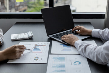 Two sales staff are working together to summarize monthly sales for the manager to review and bring...
