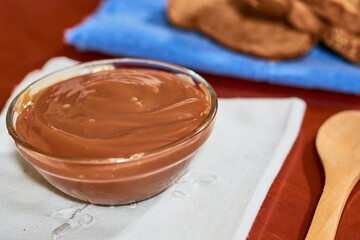 Dulce de leche in glass container, on wooden table, Cajeta. Argentine food concept.