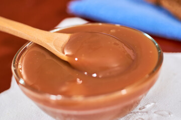 Dulce de leche in glass container, on wooden table, Cajeta. Argentine food concept.
