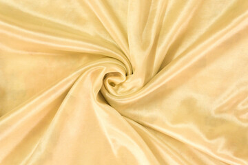 The drapery of golden satin. Luxury smooth yellow golden silk for background. Fabric rose on the drapery