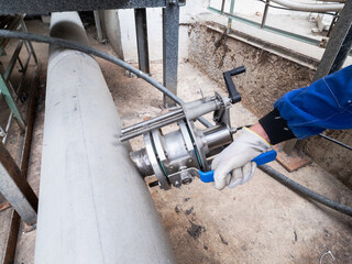 Worker closes ball valve. Stainless pipes in chemical plant