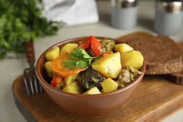 Tasty cooked dish with potatoes in earthenware on wooden board