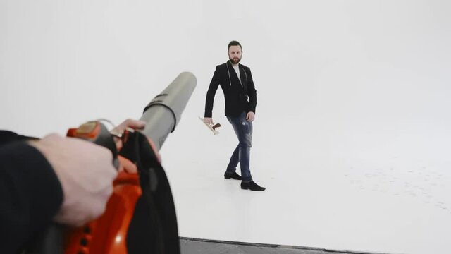 Strange man in black mask and glasses shoots vacuum cleaner at bearded brutal guy in black jacket. Office battle war, game. Persons imitates cowboys. Funny situation during duel. Adults miss childhood