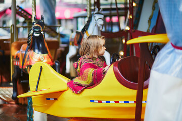 Toddler having fun on vintage French merry-go-round in Paris, France