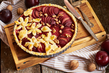 Pie with plum and nuts. Short crust pastry, chopped plums. Side view. Wooden background.