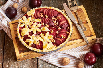 Pie with plum and nuts. Short crust pastry, chopped plums. Side view. Wooden background.