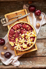 Pie with plum and nuts. Short crust pastry, chopped plums. Top view. Wooden background.
