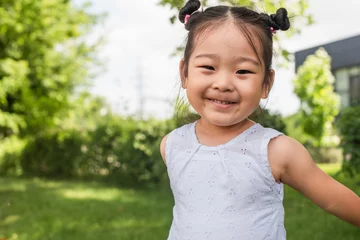 Fotobehang happy asian girl smiling and looking at camera outside © LIGHTFIELD STUDIOS