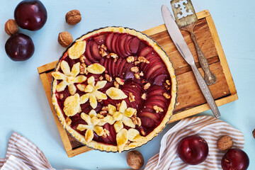Pie with plum and nuts. Short crust pastry, chopped plums. Top view. Blue background.