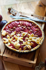 Pie with plum and nuts. Short crust pastry, chopped plums. Side view. Wooden background.