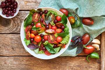 Salad with tomatoes, lettuce, cherries, hot peppers, basil.