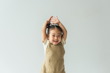 happy asian toddler girl with raised hands isolated on grey - obrazy, fototapety, plakaty