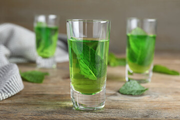 Delicious mint liqueur with green leaves on wooden table