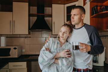 Fototapeta na wymiar Young couple drinking coffee in kitchen at home in the morning. Young happy couple, newlyweds family start new day and have morning coffee together