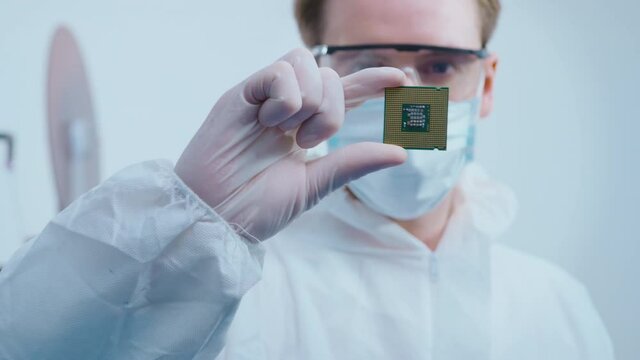 Engineer man  in sterile suit is holding Microchip with symbols in modern design factory  , futuristic and artificial intelligence concept