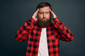 Upset and distressed, tensed young bearded guy suffering terrible migraine, massaging temples with...