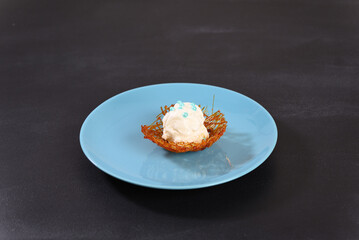 Ice cream in sugar caramel on a blue plate.
