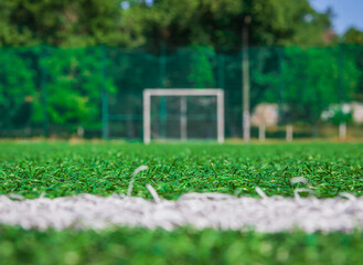 Soccer field with artificial green grass near the school. Amateur football field. Sunny summer day. Soft focus