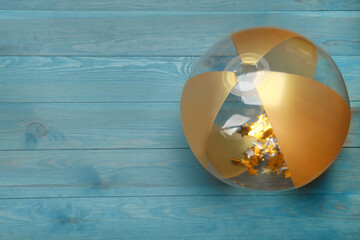 Bright beach ball on light blue wooden background, top view. Space for text