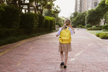 Back to school. Little girl with yellow backpack from elementary school outdoor. Kid going learn new things 1th september after end Coronavirus covid-19 quarantine and self isolation 