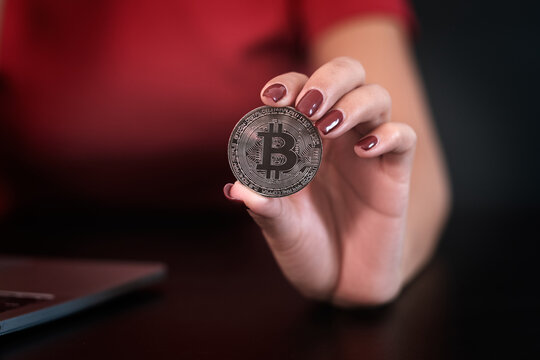 Closeup image of woman's hand  holding and showing a bitcoin coin .