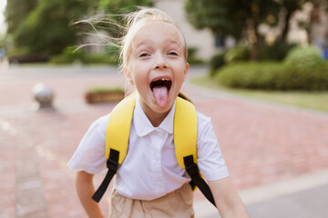 Back to school. Little girl with yellow backpack from elementary school outdoor. Kid going learn new things 1th september after end Coronavirus covid-19 quarantine and self isolation