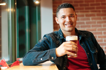 Happy attractive Hispanic man enjoying a cold beer