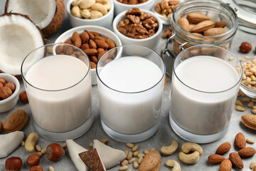 Vegan milk and different nuts on grey table