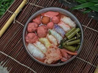 Soft dough wrapped filling with seafood and tofu meatball in red soup 