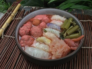 Soft dough wrapped filling with seafood and tofu meatball in red soup 