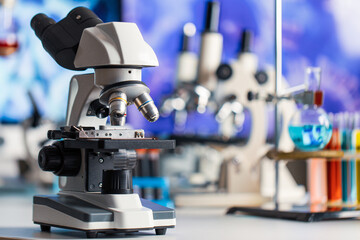 Microscope in and laboratory with chemical test tube equipment in lab blue lights, science and experiment concept with copy space