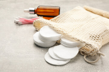 Cotton pads, swabs and makeup removal product on grey table, closeup