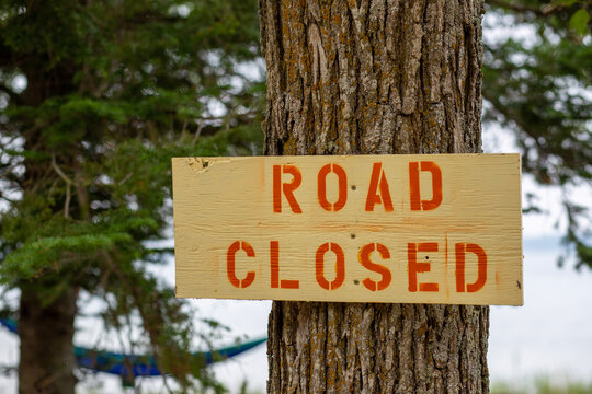 A sign that states the road is closed - bear wood and red letters made with stencils and spray paint