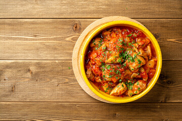 Traditional georgian dish Chakhokhbili. Chicken stew with tomatoes in ceramic bowl on wooden...