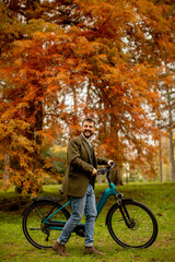 Handsome young man with electric bicycle in the autumn park