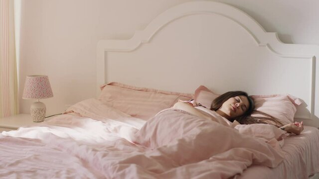 A further back angle of a beautiful brown haired woman sleeping in her cute pyjamas and duvet set