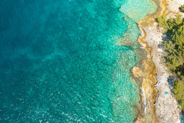 Top view of rocky shore in turquoise blue water of Adriatic Sea with copy space.