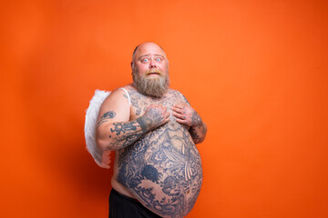 Fat amazed man with beard ,tattoos and wings acts like an angel
