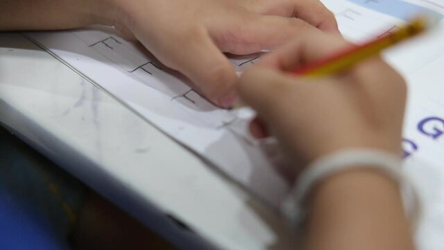 Kindergarten children are learning to write English exercises at home.