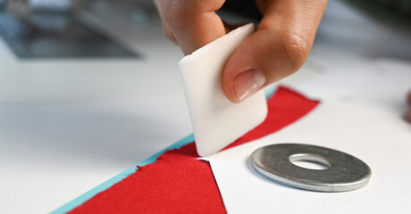 Closeup of unrecognizable skilled tailor working in atelier: hands marking fabric with chalk while making clothes on table