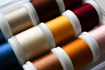 Spools of colored thread are lying side by side. Sewing thread selection.