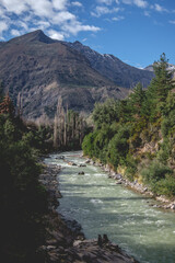 Beautiful view of the Maipo River, blue sky and the hills of the Andes Mountains with a lovely couple of travelers in the bottom in a sunny day